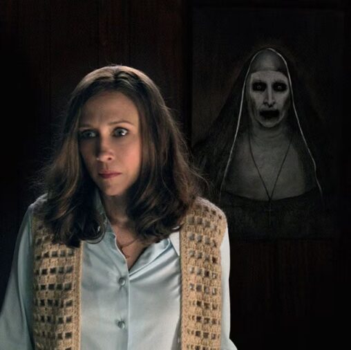 Woman standing in front of a dark wall while a ghostly nun figure looms behind her in the shadows